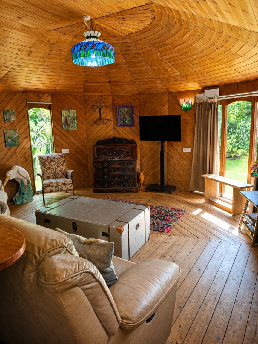 Cosy living room with timber walls, wooden floors and a stained-glass light